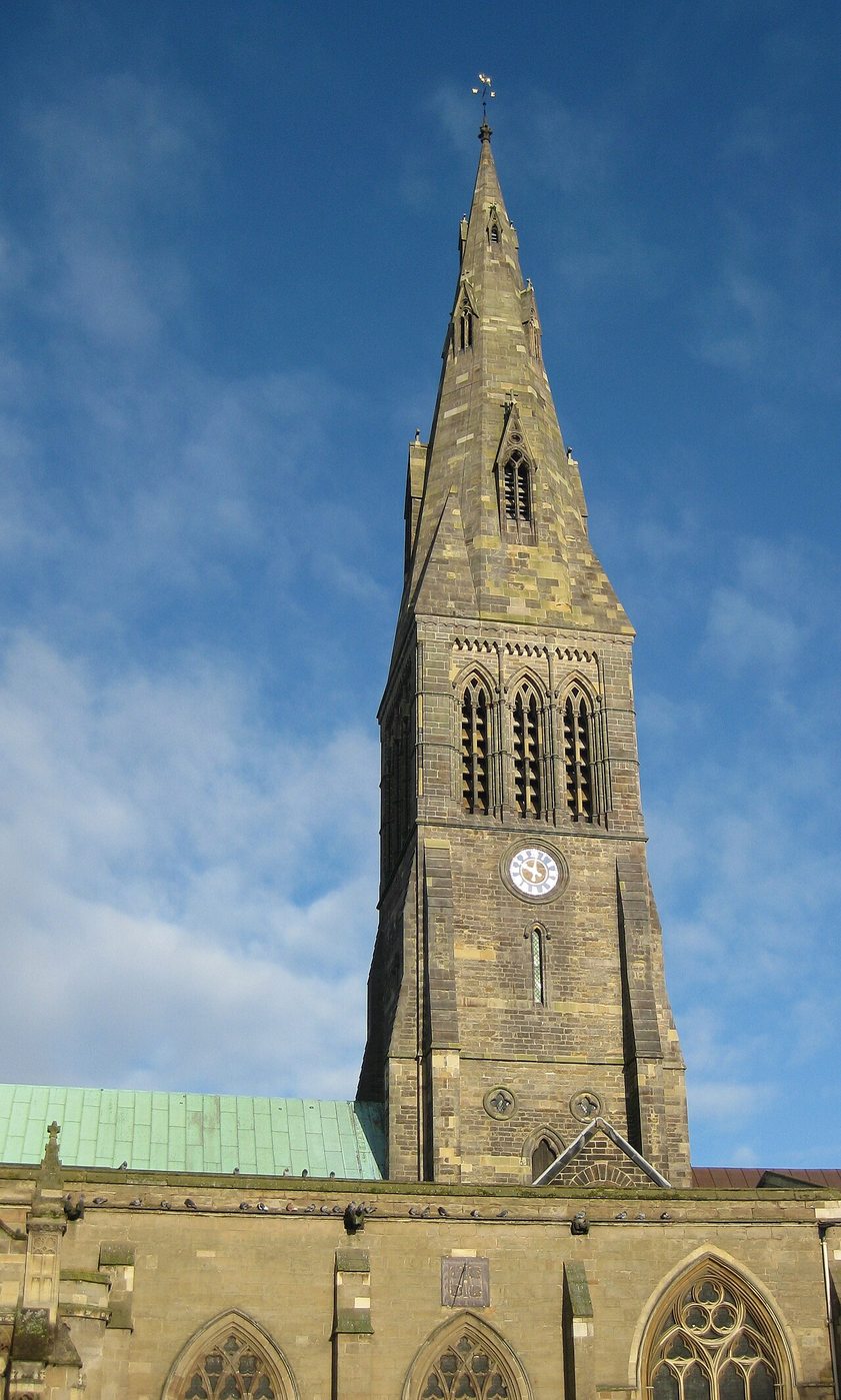 The tall stone spire of Leicester Cathedral against a blue sky