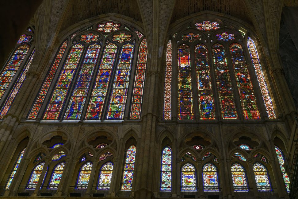 Tall Gothic stained-glass windows in León Cathedral glowing in blues, reds and golds