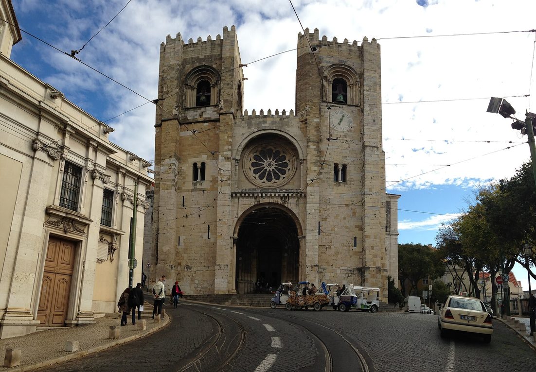 The fortress-like west front of Lisbon Cathedral, with two crenellated towers either side of a rose window
