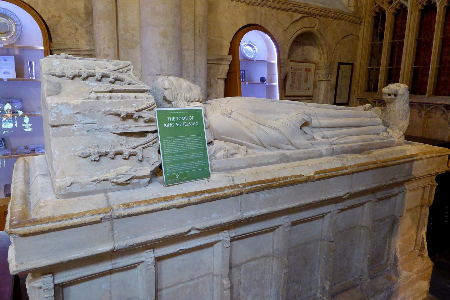 A carved stone tomb chest with a recumbent crowned effigy, in Malmesbury Abbey