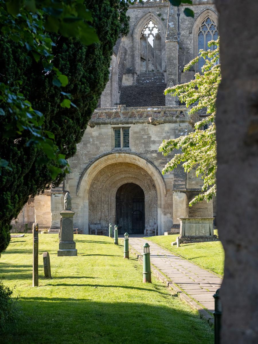 A path through the churchyard leading to the round-arched south porch of Malmesbury Abbey