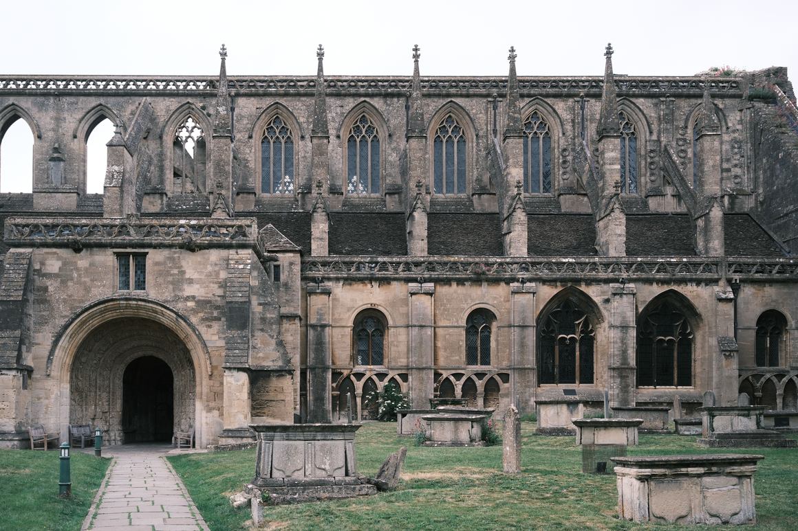 The south side of Malmesbury Abbey with its great Norman porch, pinnacled parapet and churchyard tombs