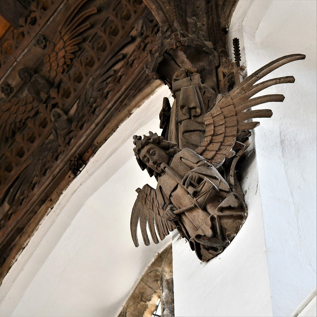 A carved wooden angel with wings outspread at the end of a hammerbeam in the roof at March
