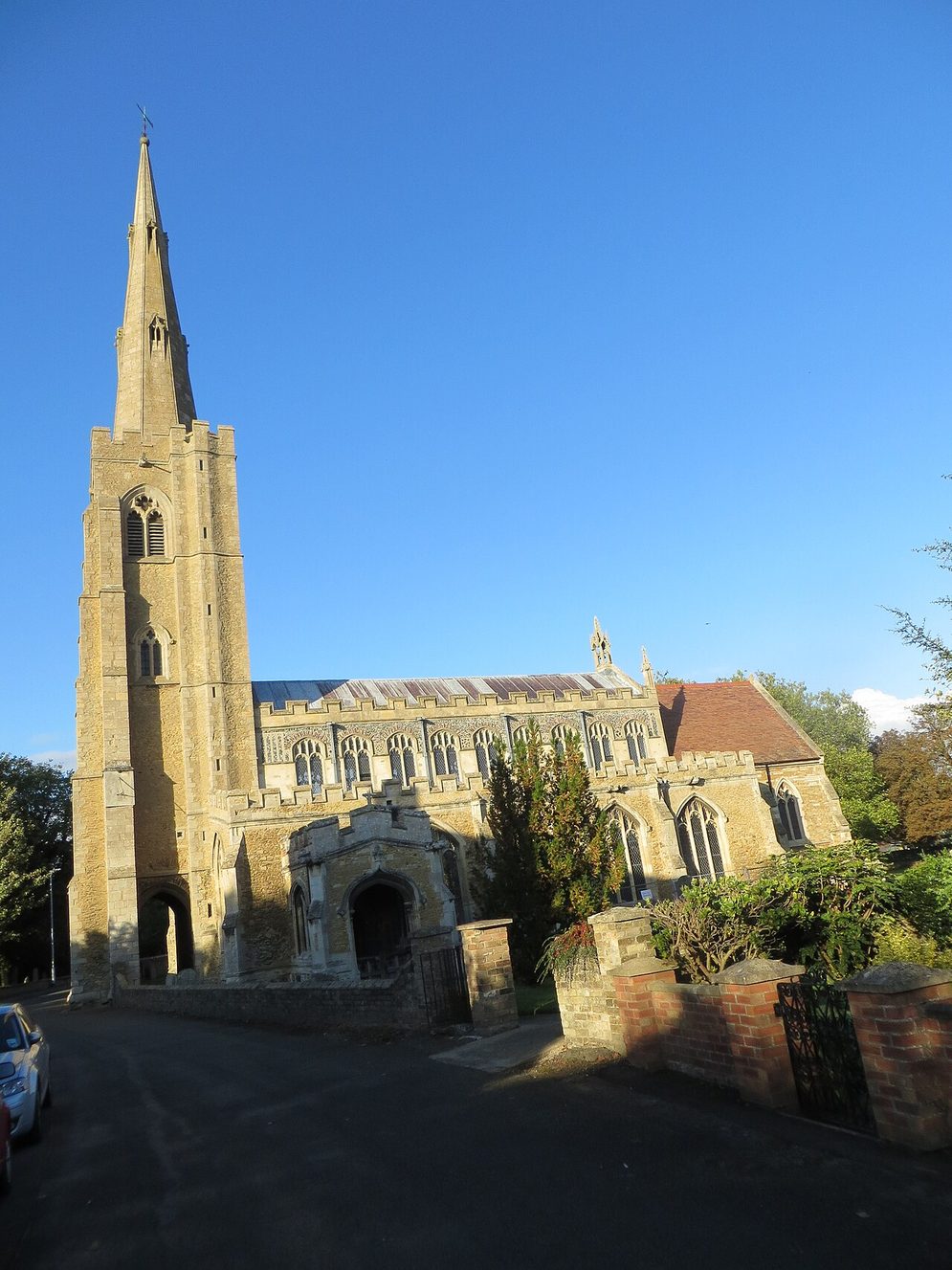 The west tower and tall stone spire of St Wendreda's Church, March, against a clear blue sky