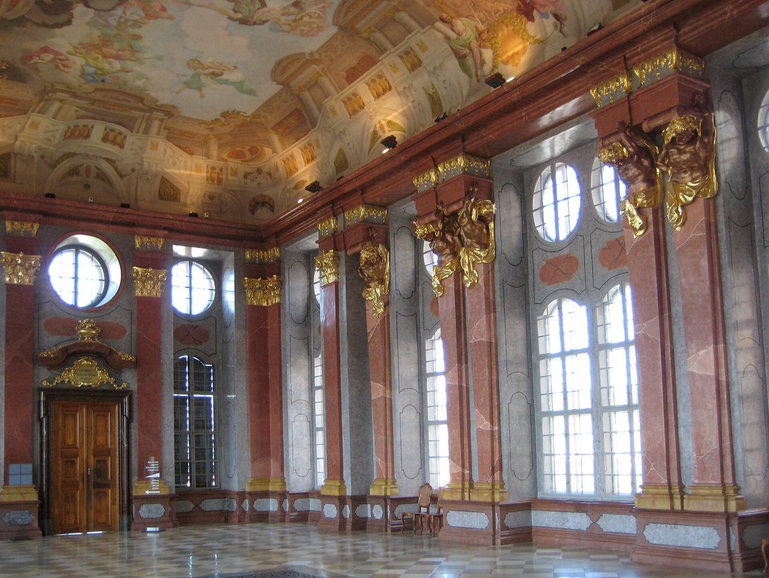 The Marble Hall of Melk Abbey, with pink marble pilasters, tall windows and a painted ceiling