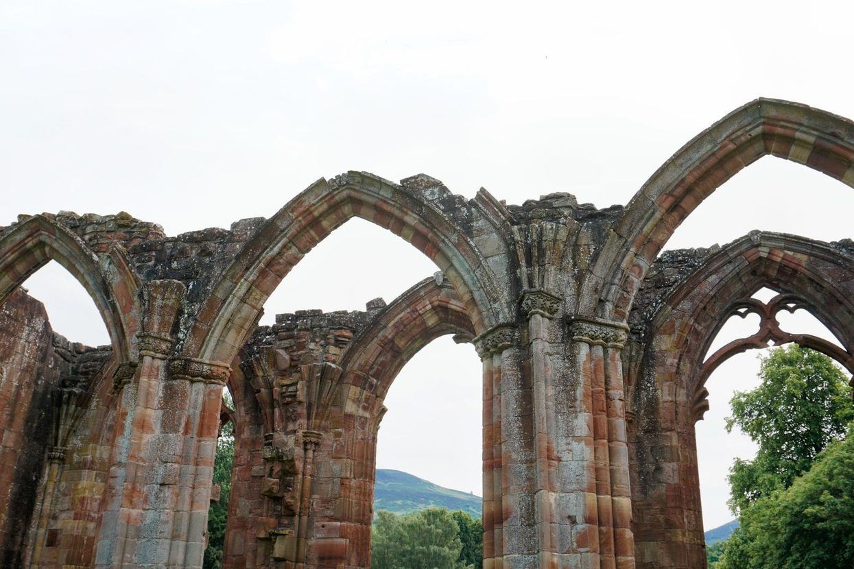 Ruined pointed arches and pillars of the nave at Melrose Abbey, open to the sky