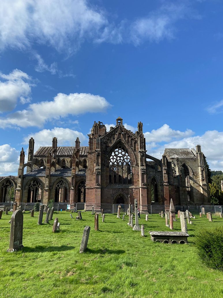 The south transept of Melrose Abbey with its great traceried window, seen across the graveyard