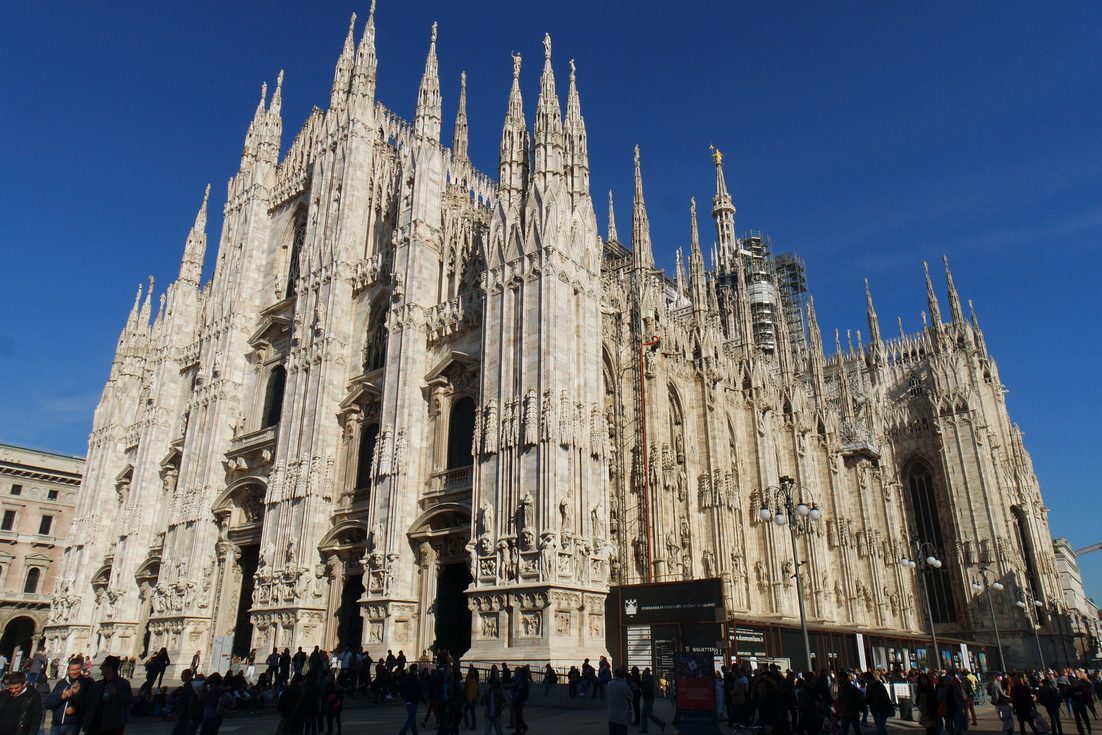 Milan Cathedral seen from the corner of the piazza, showing the facade and the forest of spires along its side
