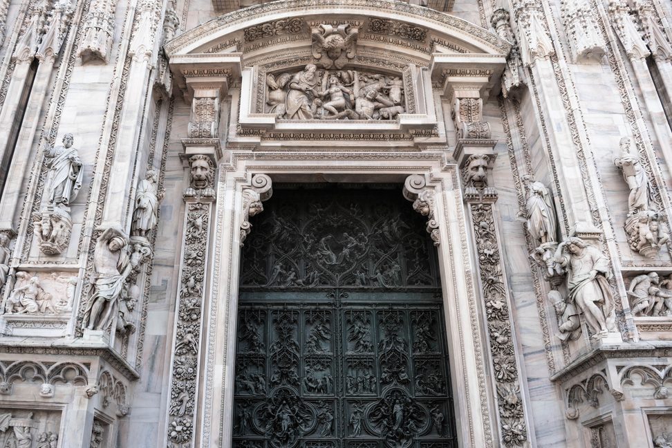A bronze door set in the carved marble central portal of Milan Cathedral