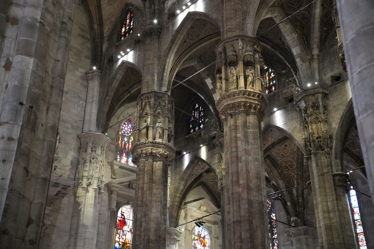 Stained-glass windows glowing between the piers of Milan Cathedral