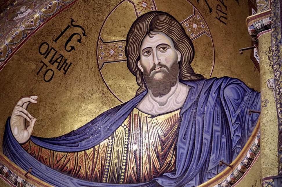 Close view of the mosaic Christ Pantocrator in the apse of Monreale Cathedral, his right hand raised in blessing