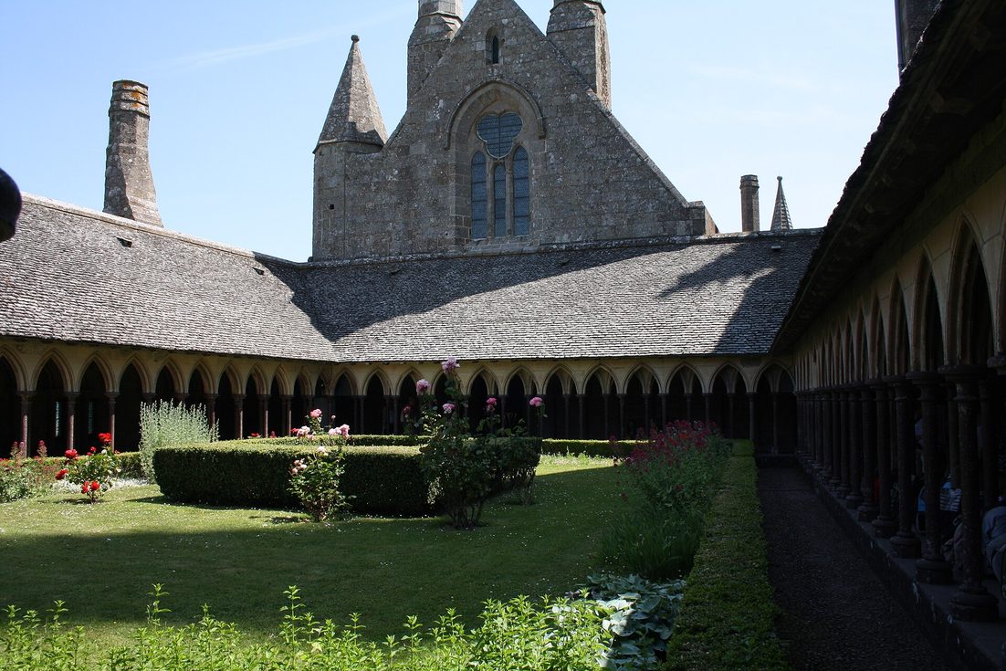 The cloister of Mont-Saint-Michel, with slender arcades round a garden and the abbey church above