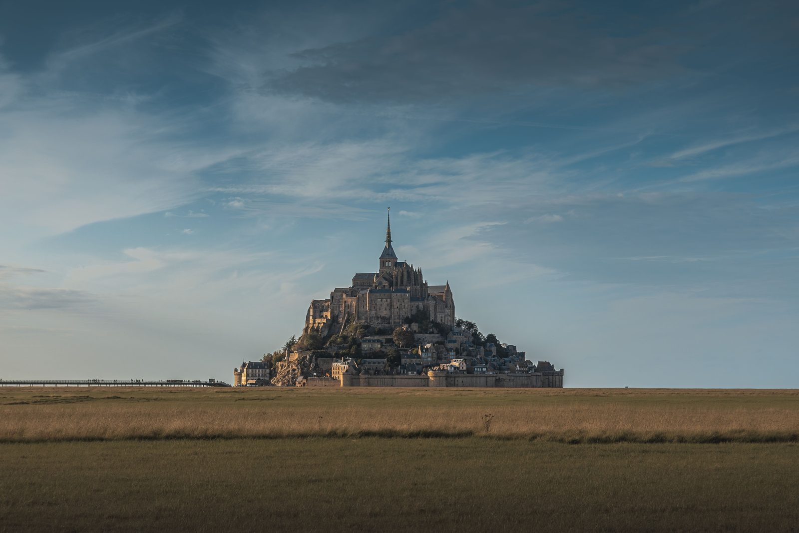 Mont-Saint-Michel seen across the flat fields and salt meadows at dusk