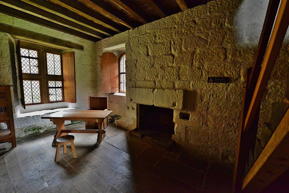 The living room of the reconstructed monk's cell at Mount Grace Priory, with a table, fireplace and leaded window