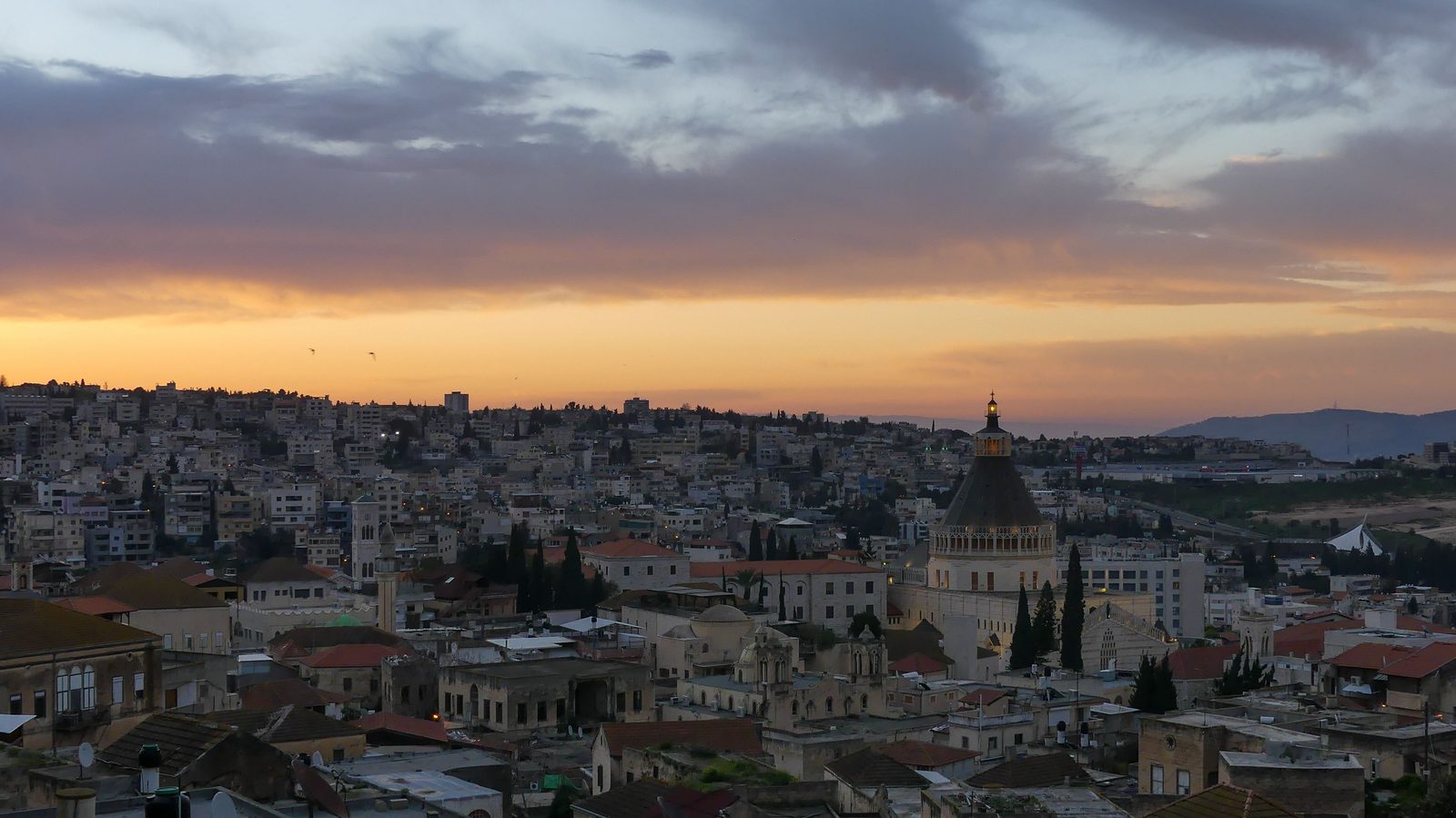 Nazareth at sunset, its hillside houses spreading round the dome of the Basilica of the Annunciation