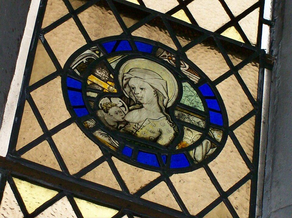 A medieval stained-glass roundel of the Virgin Mary holding the Christ Child, set in clear leaded glass