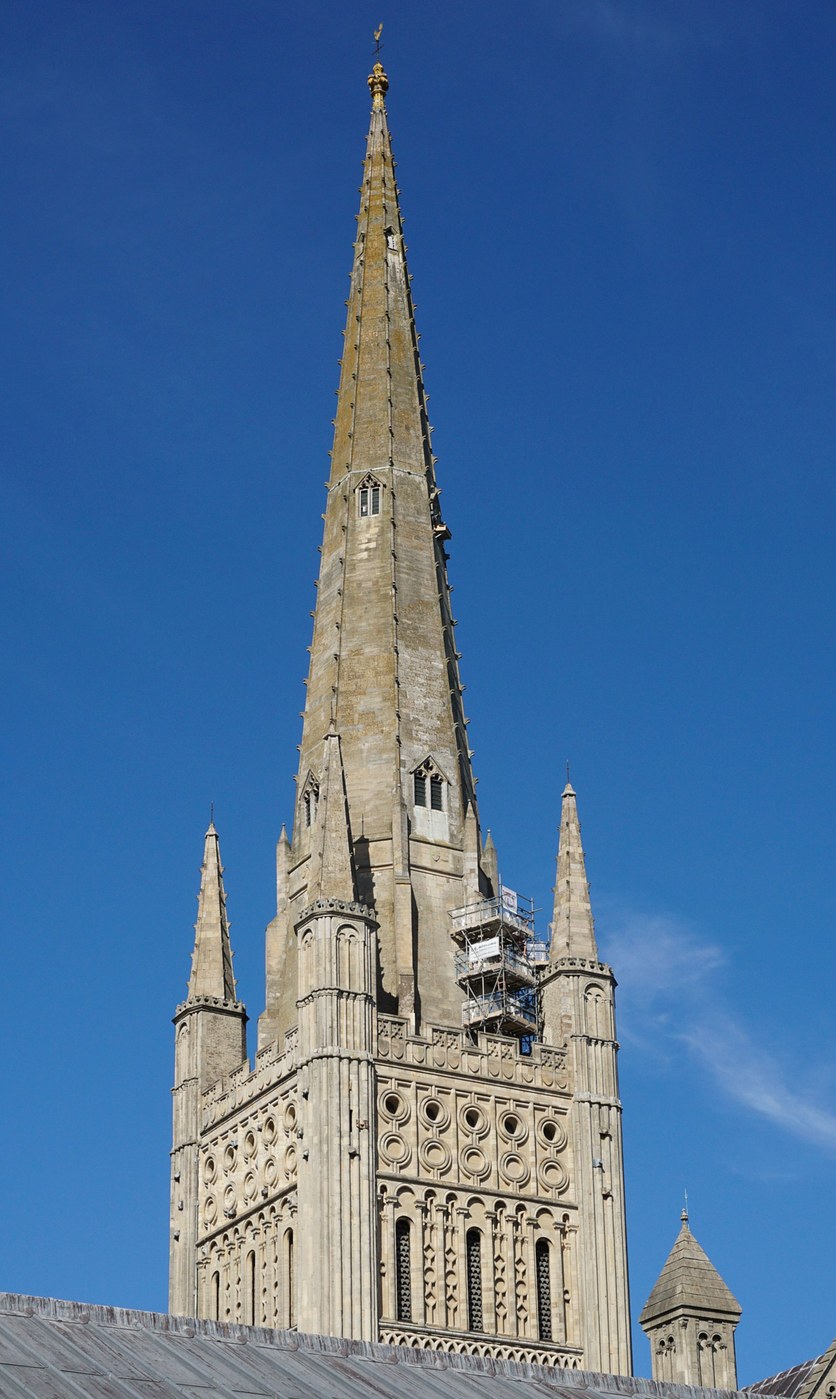 The tall stone spire and Norman tower of Norwich Cathedral against the sky