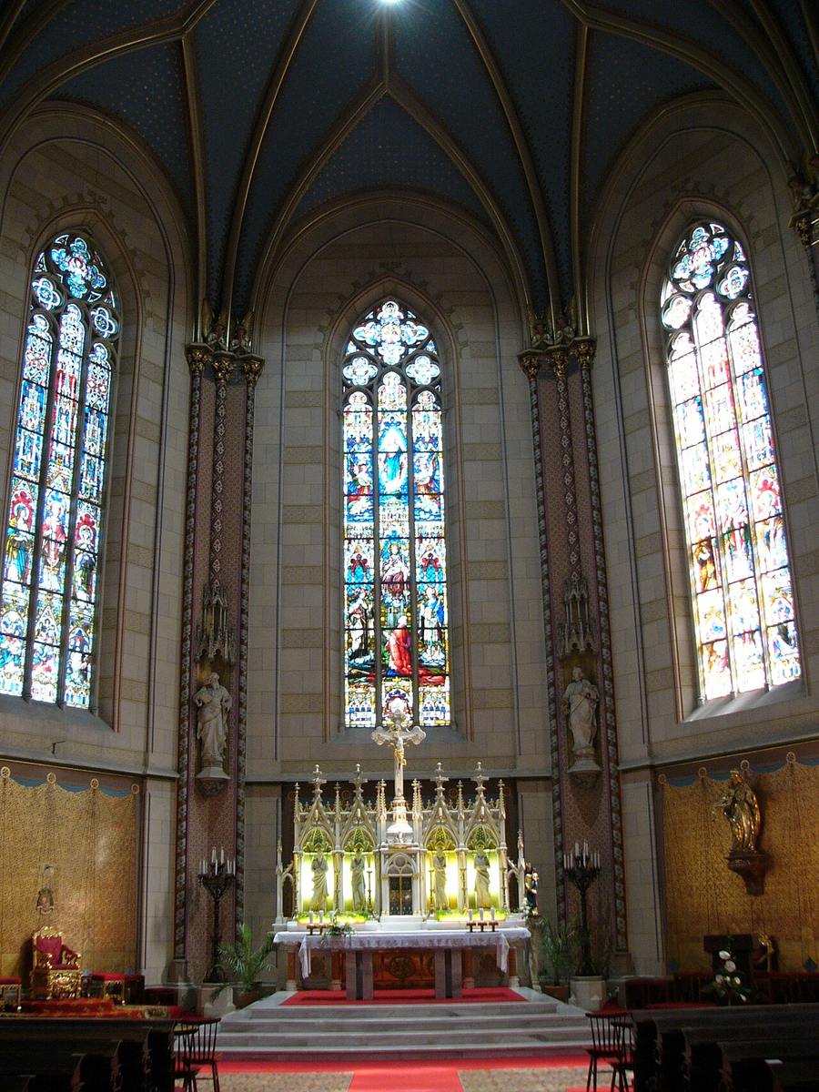 The raised presbytery and high altar of Olomouc cathedral under tall stained-glass windows