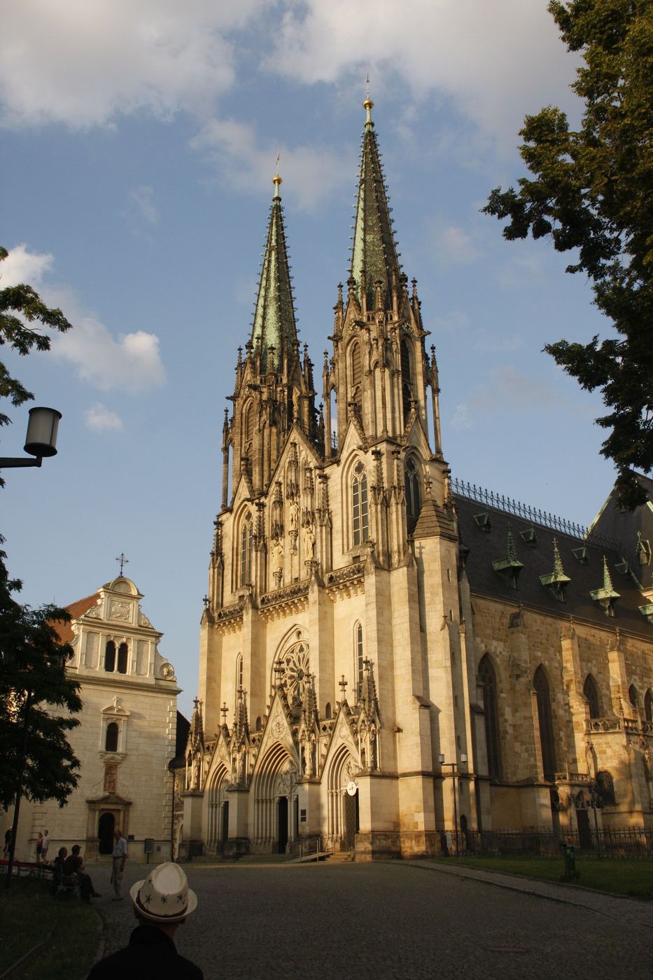 The twin-spired front of Olomouc cathedral in evening light, with St Anne's church beside it