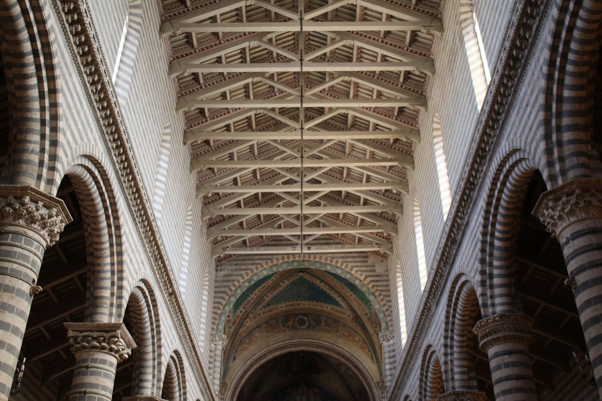The nave of Orvieto Cathedral, with striped columns and arches and an open timber roof