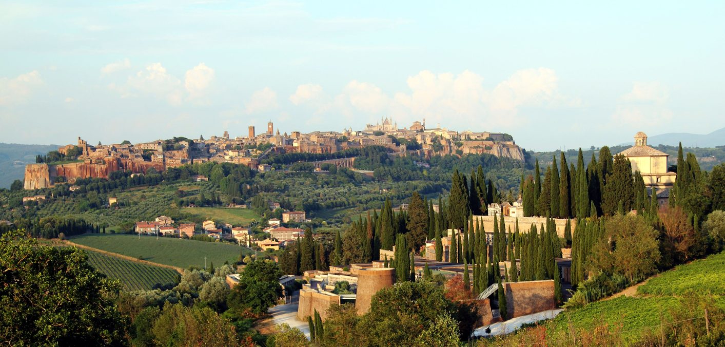 The town of Orvieto on its rock above vineyards and cypress trees, with the cathedral rising above the roofs
