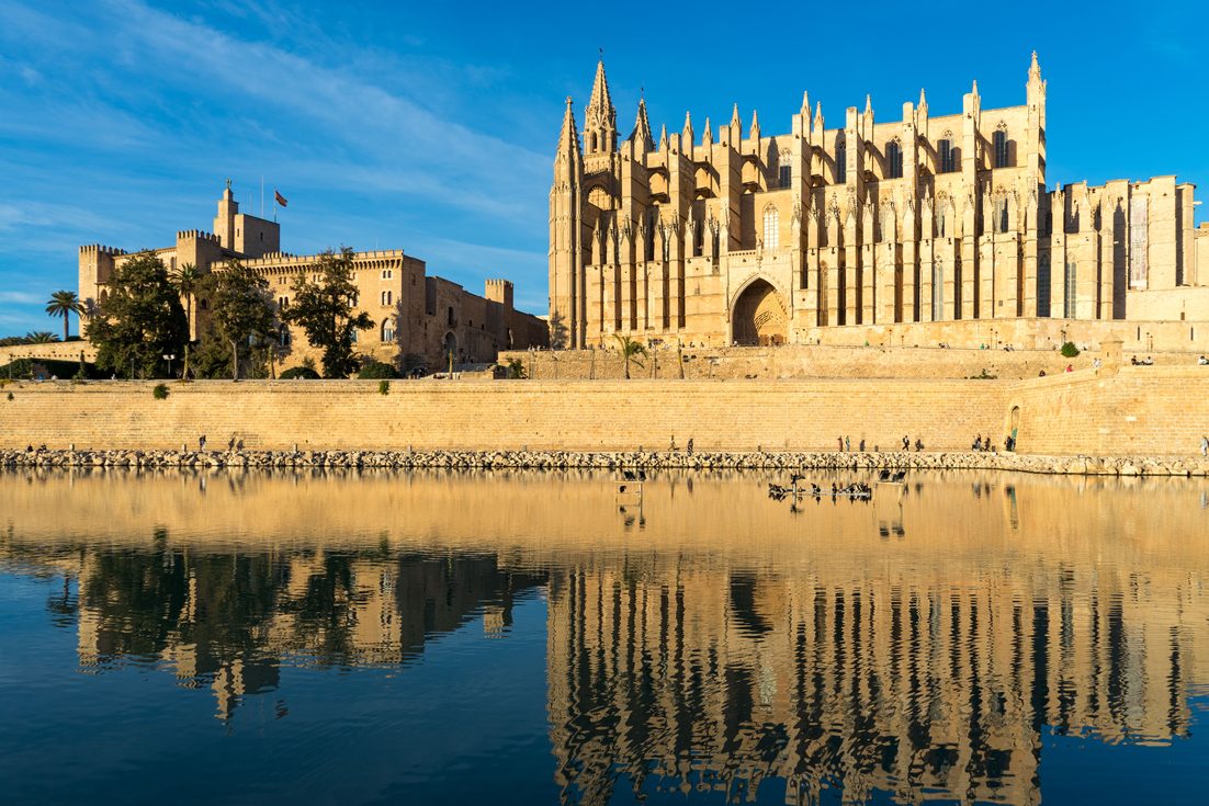 Palma Cathedral and the Almudaina palace reflected in the still water of the lake in the Parc de la Mar
