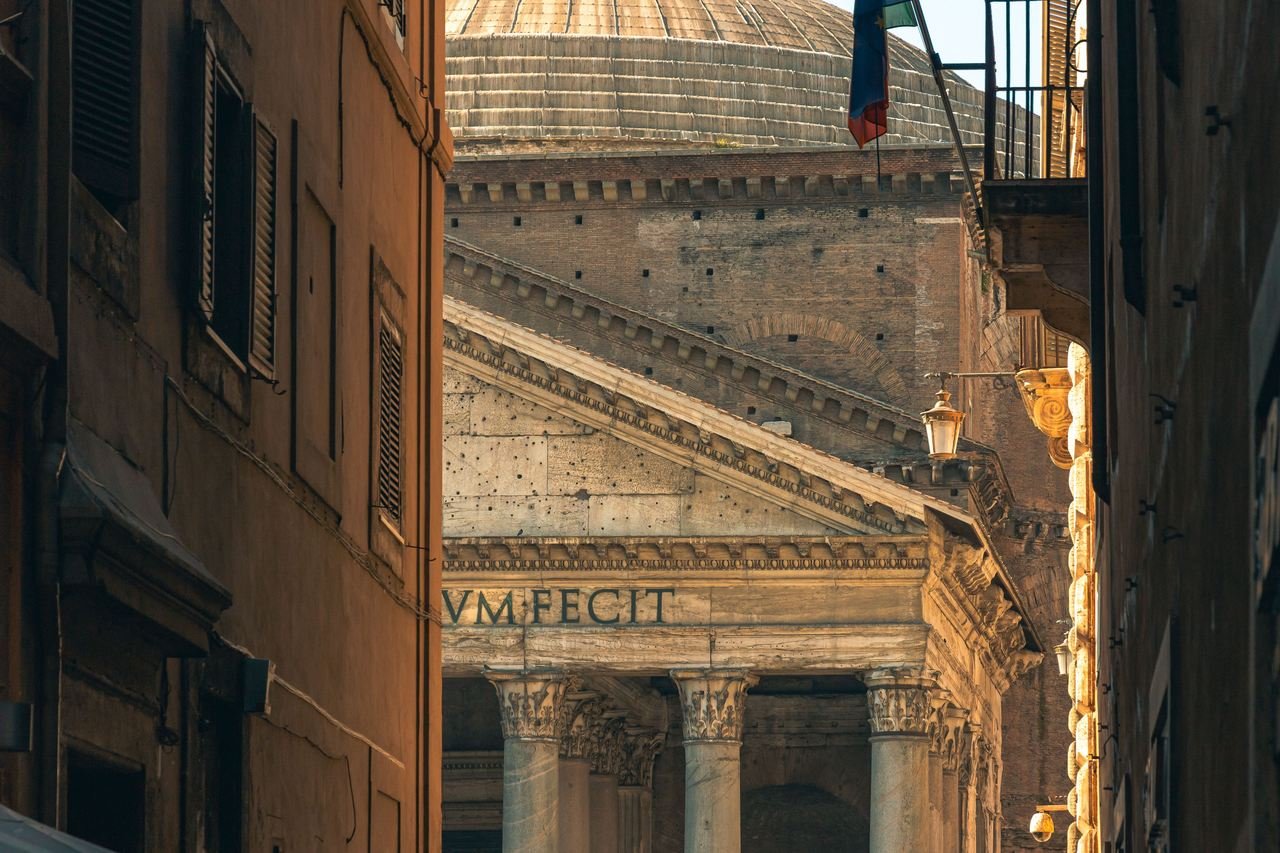 The Pantheon glimpsed at the end of a narrow Roman side street at dusk