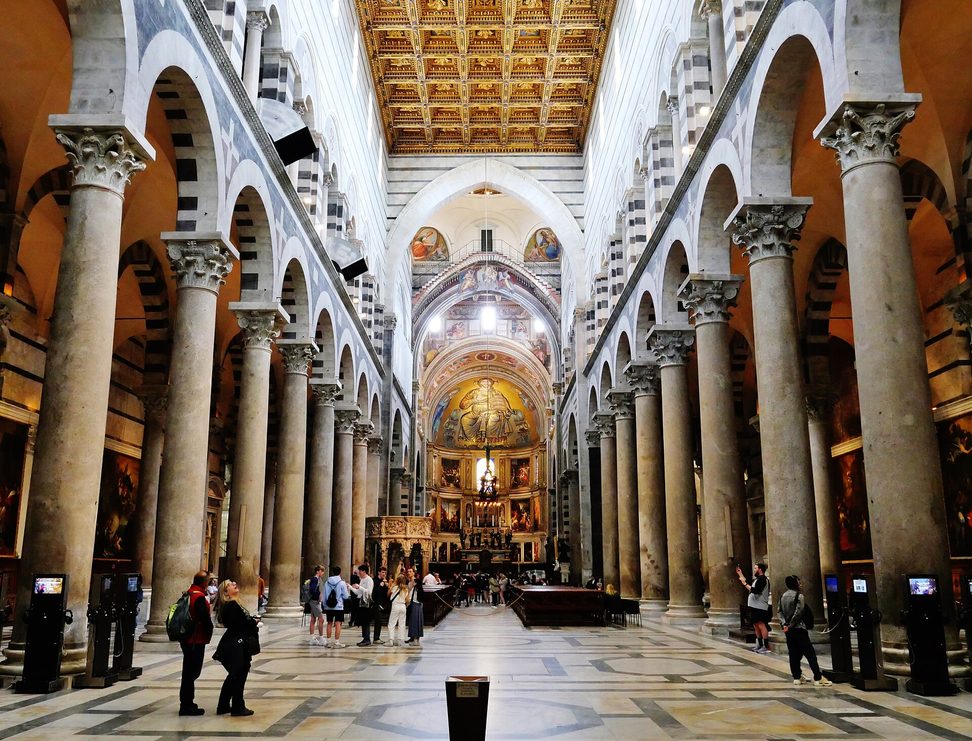 The striped arcades and granite columns of the nave of Pisa Cathedral, leading to the gold apse mosaic