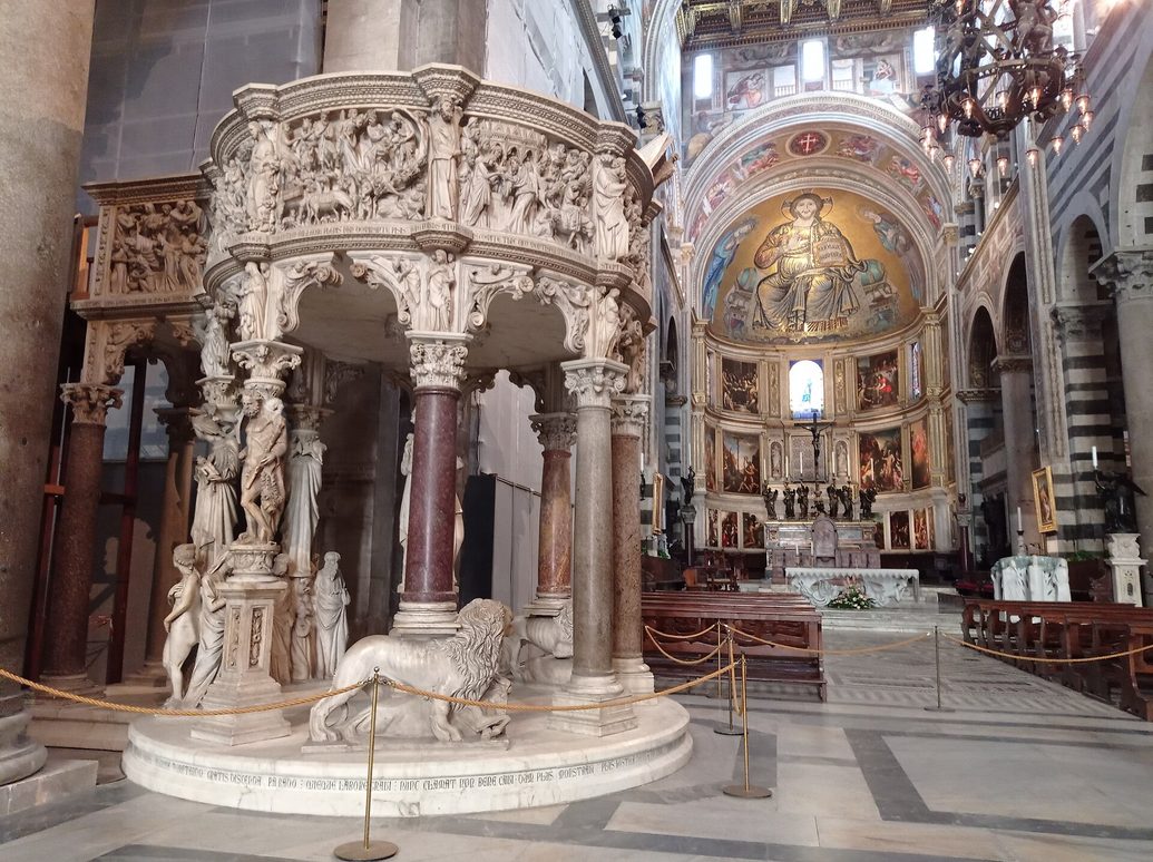 Giovanni Pisano's carved marble pulpit in Pisa Cathedral, on columns and figures, with the apse beyond