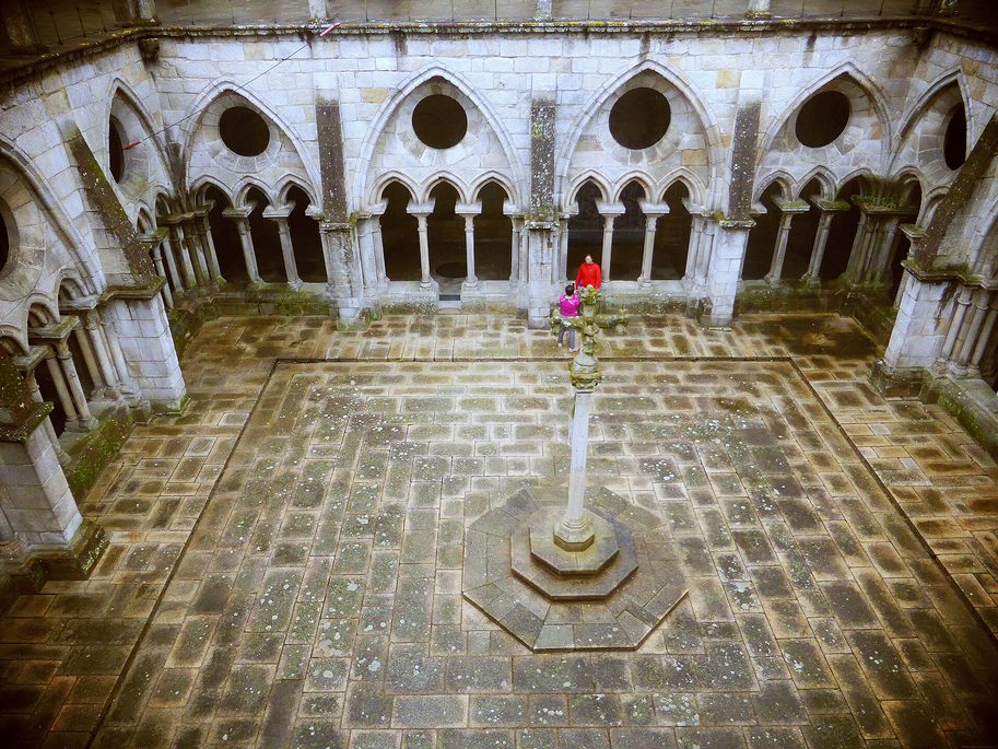 The paved courtyard of the Gothic cloister of Porto Cathedral seen from above, with a stone cross in the centre
