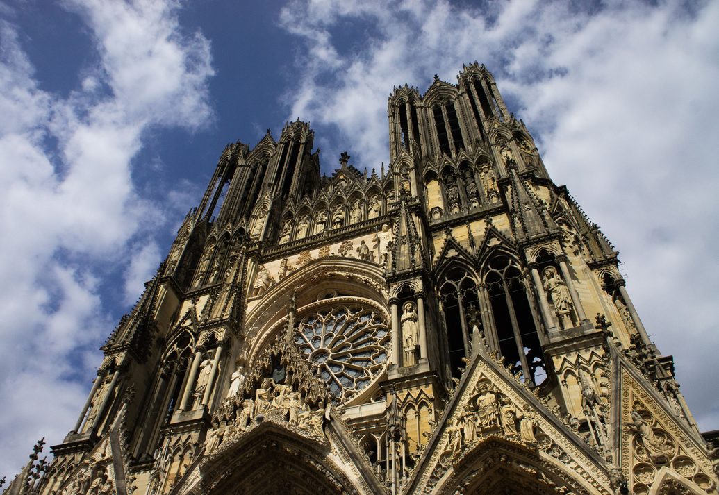 The upper west front of Reims Cathedral with the rose window and the gallery of kings below the towers