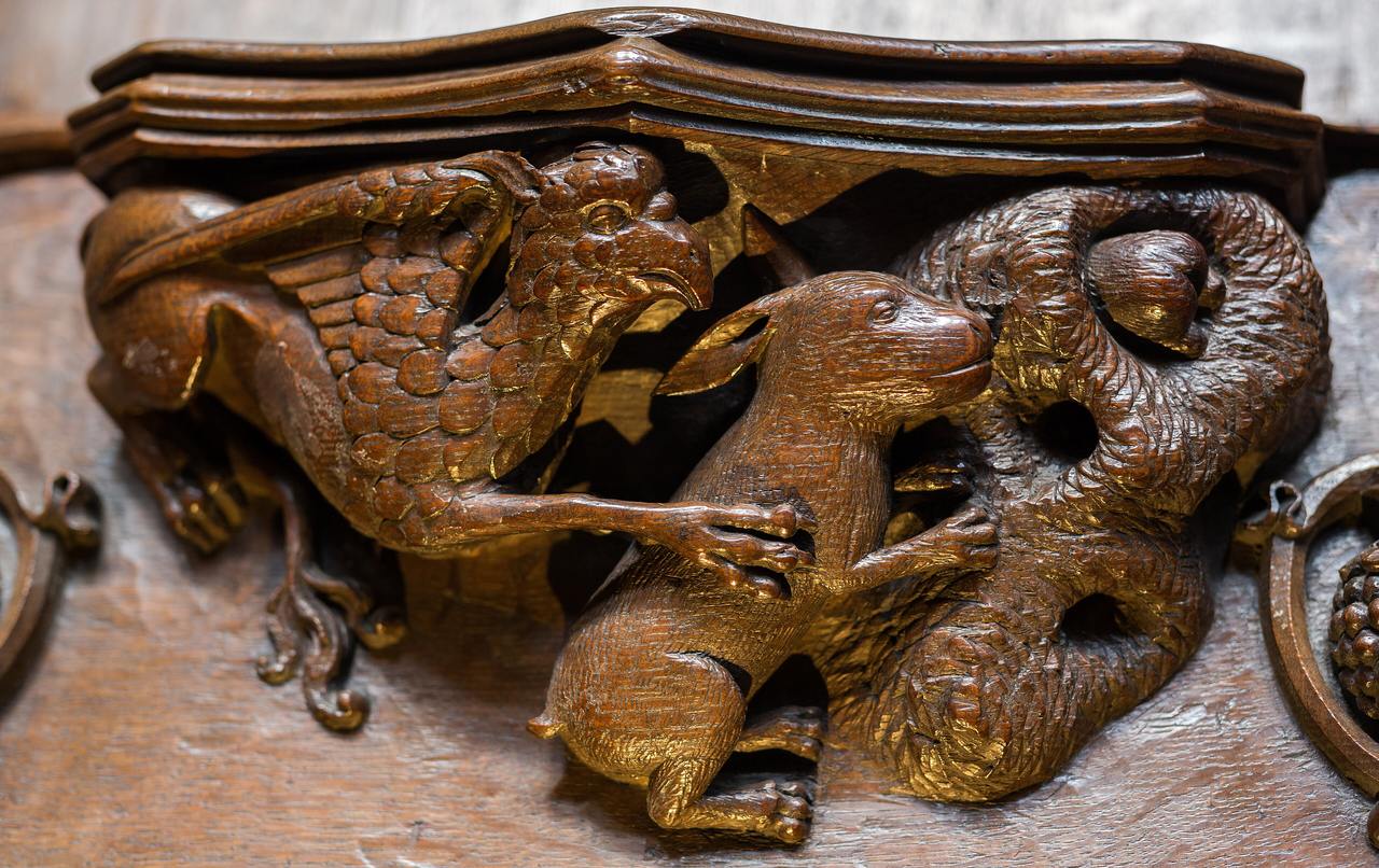 A carved wooden misericord at Ripon Cathedral showing a griffin chasing a rabbit into a hole