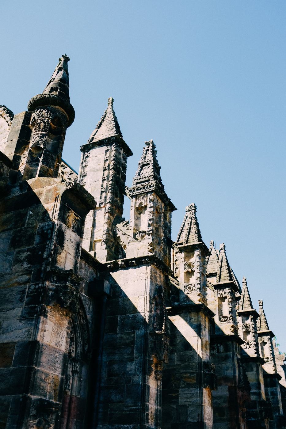 Pinnacles along the roofline of Rosslyn Chapel against a blue sky