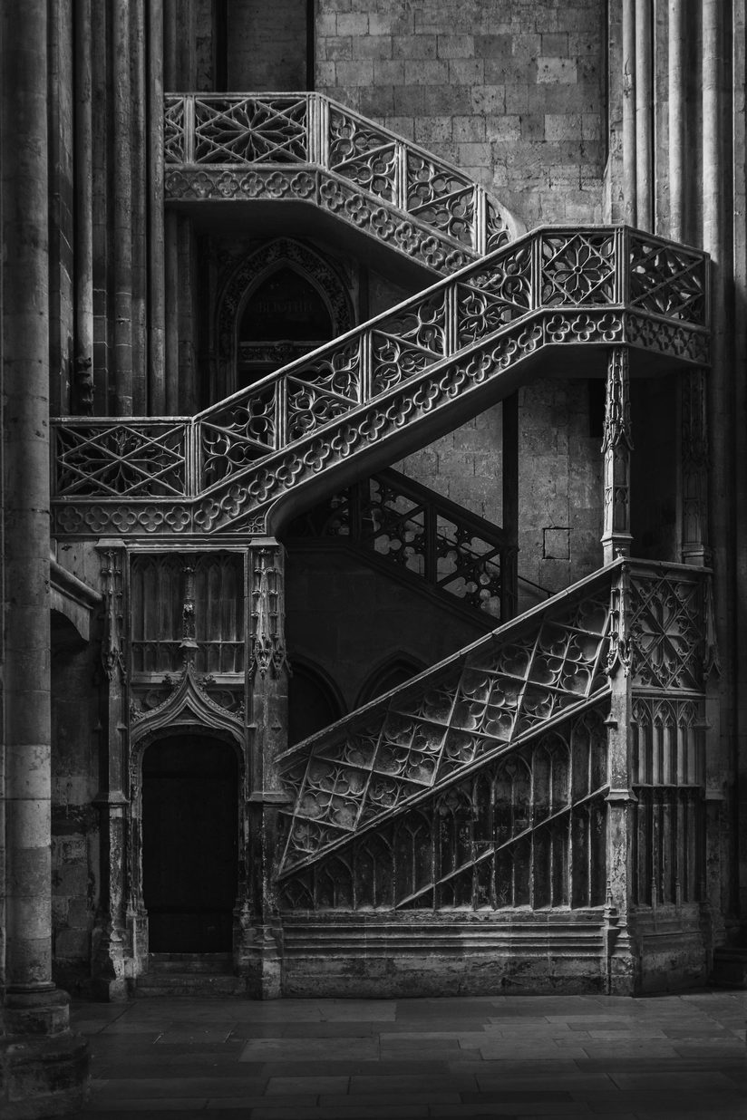 Black and white photograph of the carved Gothic stone staircase climbing the wall of a transept in Rouen Cathedral