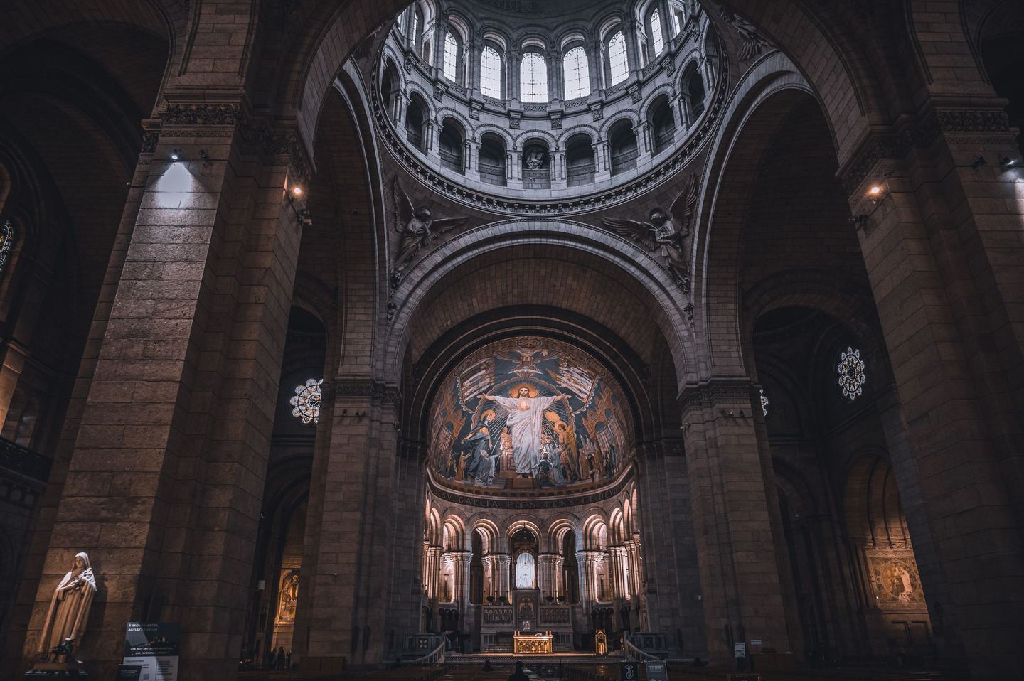 The dim interior of Sacré-Cœur looking east beneath the dome towards the apse mosaic