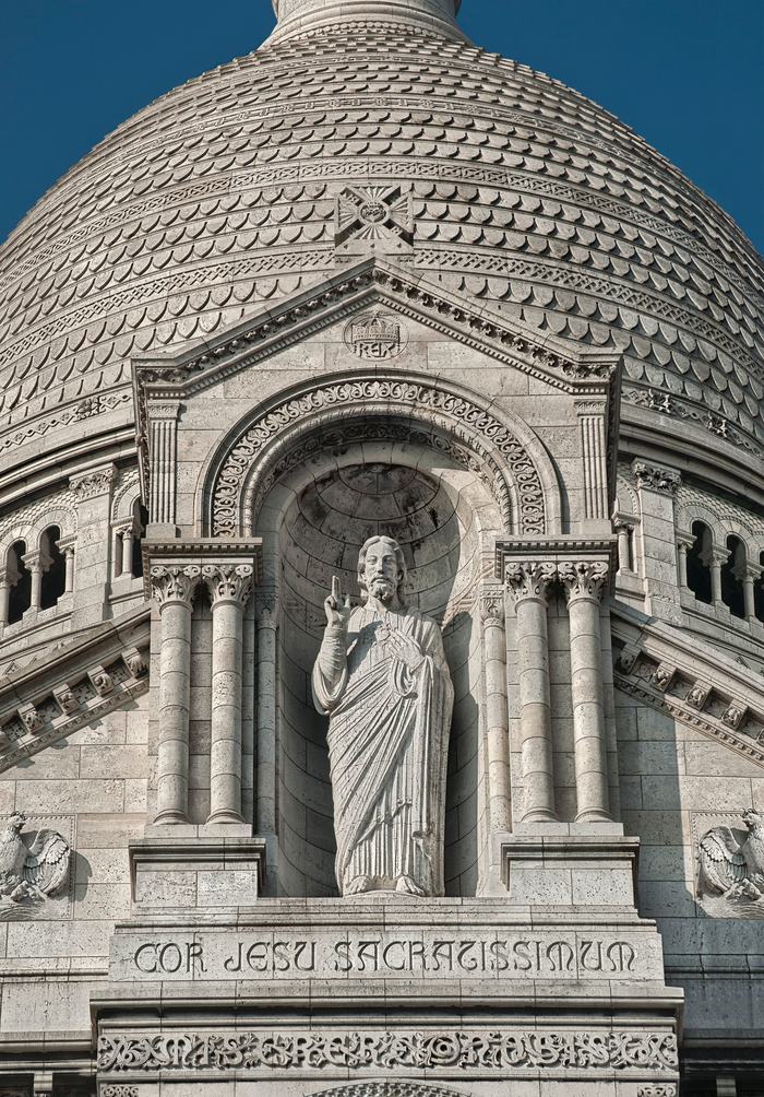 Statue of Christ in a niche on Sacré-Cœur under the inscription Cor Jesu Sacratissimum