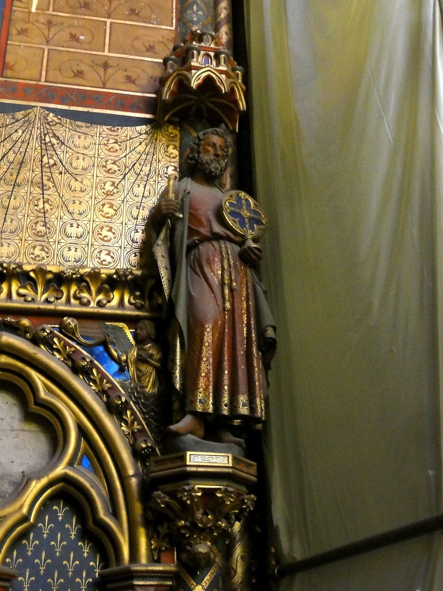 A painted statue of an apostle against a pier in the upper chapel of the Sainte-Chapelle