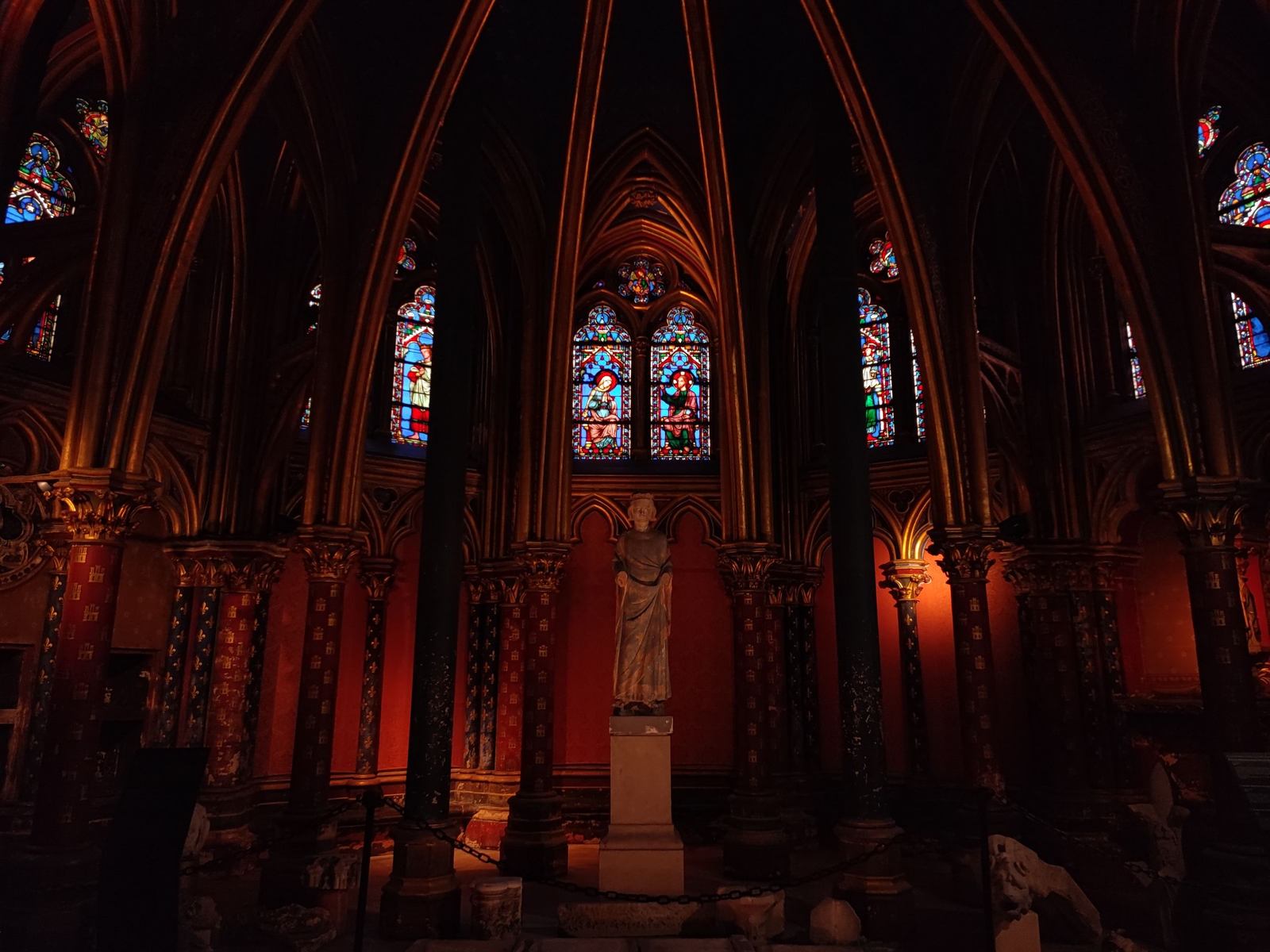 The dim, low lower chapel of the Sainte-Chapelle with a statue of Louis IX