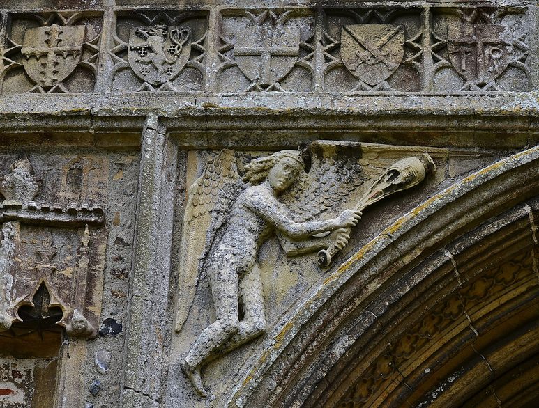 Carved stone figure of an angel swinging a censer above the west door of Salle church