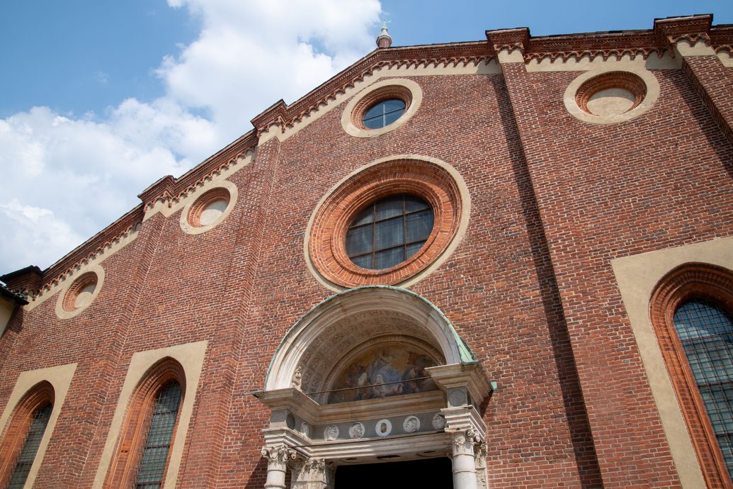 The brick facade of Santa Maria delle Grazie with its round windows and Renaissance portal