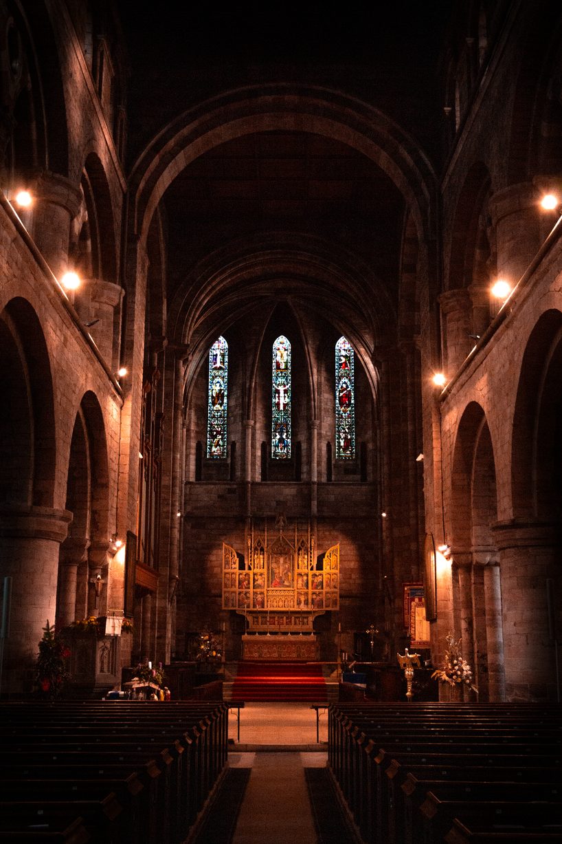 The nave of Shrewsbury Abbey looking east between round Norman piers to the lit chancel and three lancet windows
