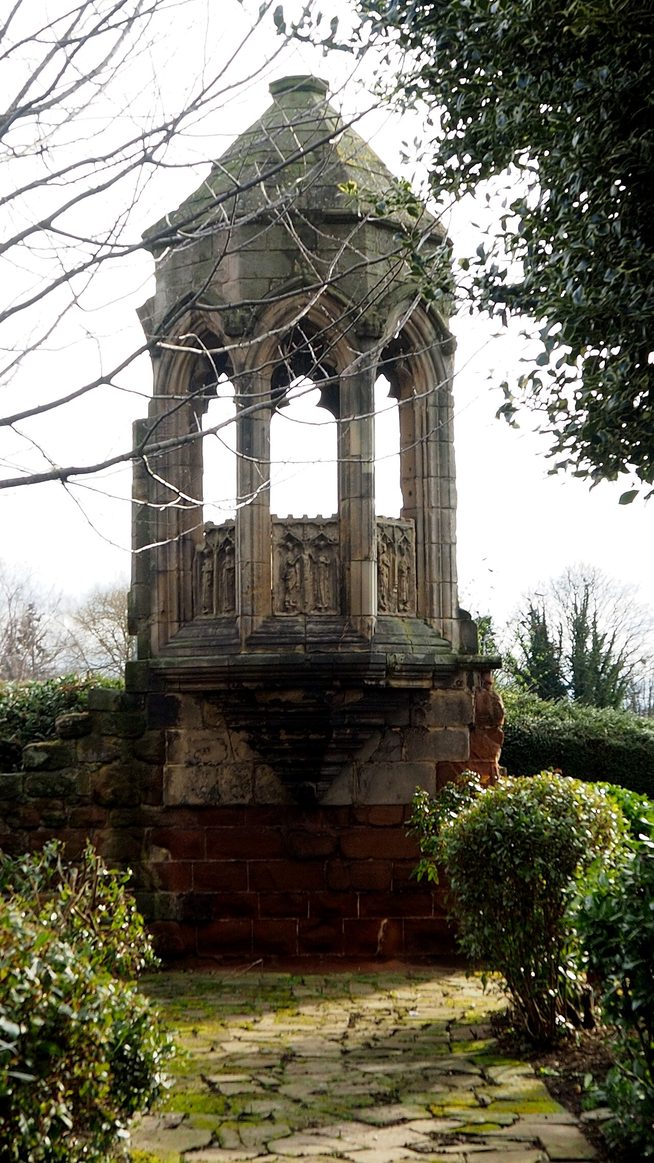 The ruined stone refectory pulpit of Shrewsbury Abbey, a small open-sided stone structure standing by the road