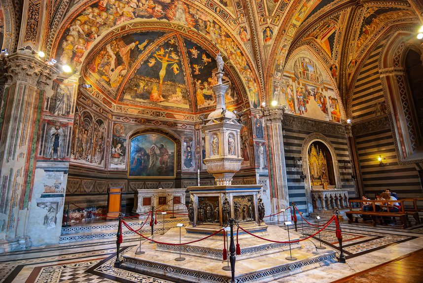 The frescoed Baptistery of Siena with the hexagonal marble and bronze font in the middle