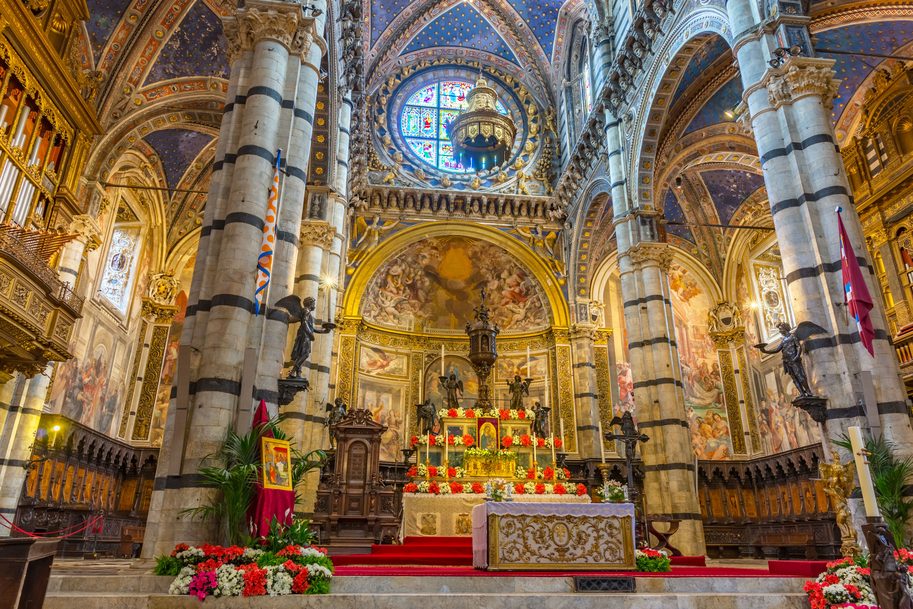The high altar of Siena Cathedral beneath the rose window, with bronze angels and striped columns
