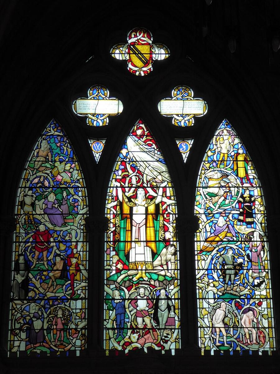 A colourful stained-glass window above the Shakespeare memorial, with figures from his plays