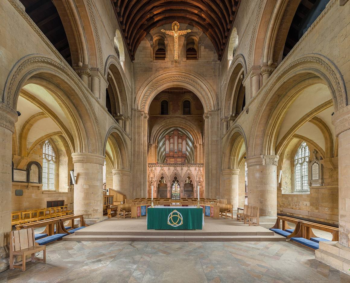 The Norman crossing of Southwell Minster with round arches, the nave altar and the stone screen beyond