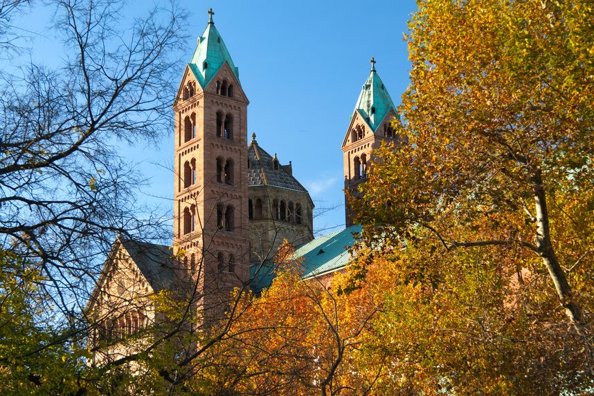 The towers of Speyer Cathedral among autumn trees under a blue sky