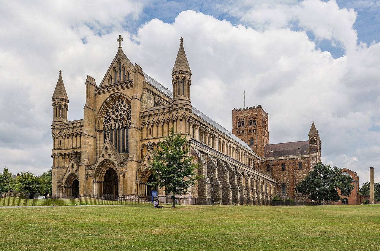 St Albans Cathedral seen from the west across the grass, with its long nave and Norman tower