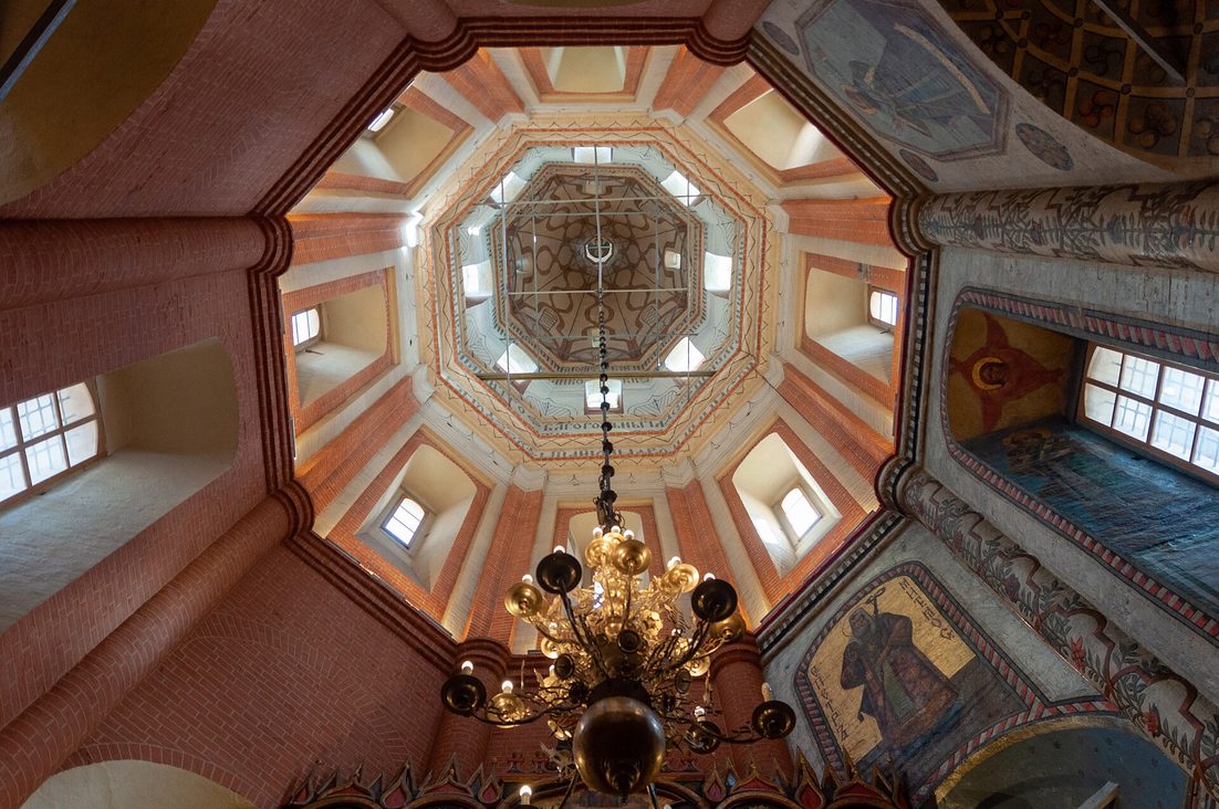 Looking up into the painted octagonal tower of one of the churches of St Basil's Cathedral, with a hanging chandelier