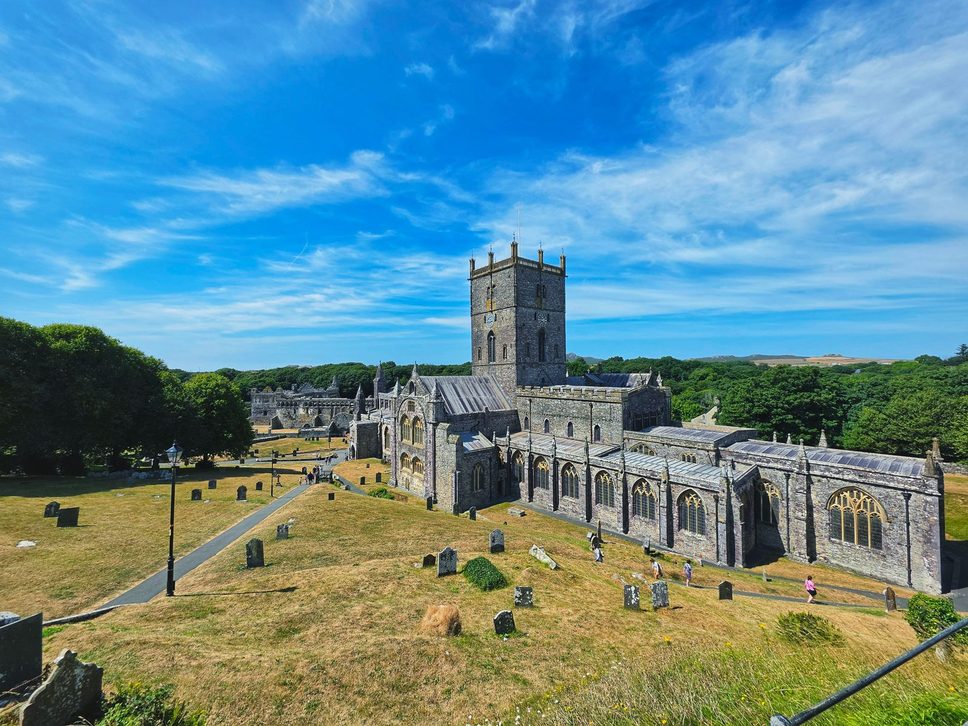 St Davids Cathedral seen from the slope above, in a grassy hollow with the countryside behind